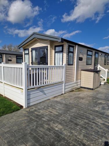 a mobile home with a porch and a white fence at AMC Flamingo Land Caravan, Motorhome & Campervan Hire in Kirby Misperton