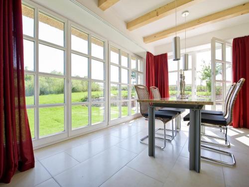 a dining room with a table and chairs and large windows at Reethaus Ostseeblick 1 A in Wohlenberg