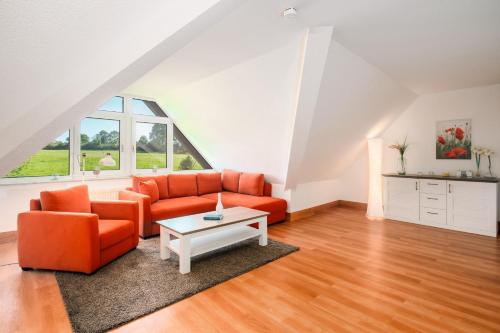a living room with an orange couch and a table at Strandhaus Lobbe, Mohnblume Nr 20 - Bade- & Saunawelt täglich inklusive in Middelhagen