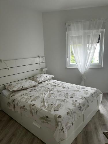 a bed in a white bedroom with a window at Monami- Apartman Mia in Vodice