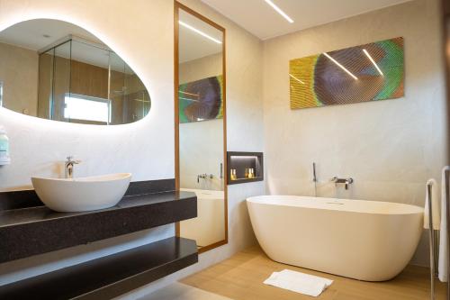 a bathroom with a tub and a sink and a mirror at Hotel Equinocios Executive in Barcarena