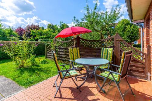 a table and chairs with a red umbrella on a patio at Ferienwohnung Edda in Klütz