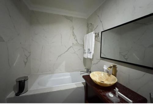 a bathroom with a sink and a tub and a mirror at Marcsons Hotels and Resorts in Limbe