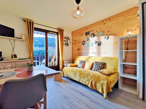 a living room with a bed and a table and a desk at Appartement Lélex - classé meublé de tourisme 2 étoiles - 4 personnes - pied des pistes - vue montagne in Mijoux