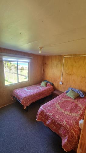 two beds in a room with a window at cabañas cubero in Gualaihue