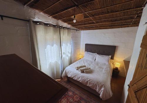 a bedroom with a bed with two towels on it at Fisherman's Cottages at Blombosch Game Farm in Yzerfontein