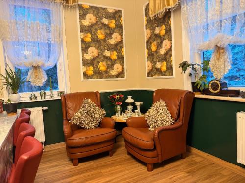 a living room with two chairs and a table at Antique Hotel Am Bahndamm in Wallendorf
