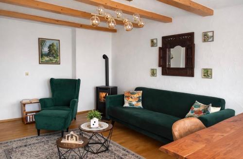 ein Wohnzimmer mit einem grünen Sofa und zwei Stühlen in der Unterkunft MPK Motorsport Apartment in Waldsassen