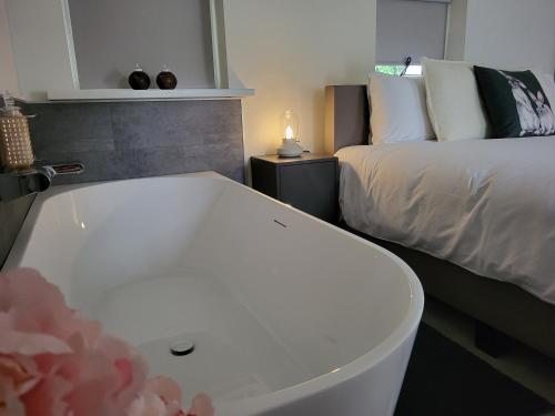 a bathroom with a bath tub next to a bed at Dalerheugte Drenthe B&B Wellness 6 met romantisch bad en ontbijt à la carte op de kamer in Dalerveen