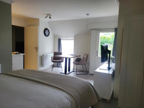 a bedroom with a bed and a table with chairs at Dalerheugte Drenthe B&B Wellness 6 met romantisch bad en ontbijt à la carte op de kamer in Dalerveen