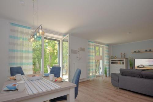 a living room with a table and a couch at Haus Waldidyll, Küstenflair - Bade- & Saunawelt täglich inklusive in Ostseebad Sellin