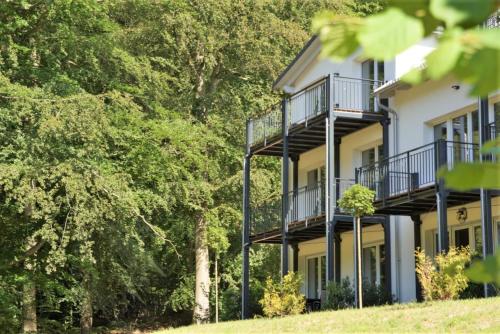 a white house with balconies and trees at Haus Waldidyll, Küstenflair - Bade- & Saunawelt täglich inklusive in Ostseebad Sellin