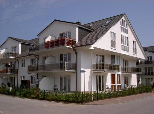 a white apartment building with a black roof at Ostseebrise - Bade- & Saunawelt täglich inklusive in Thiessow