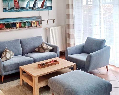 a living room with two blue couches and a coffee table at Ostseebrise - Bade- & Saunawelt täglich inklusive in Thiessow