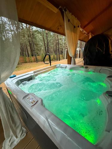 a hot tub in a tent with green illumination at Forest Home Dębowa 18 in Łuka