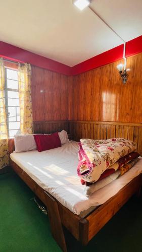 a large bed in a room with wooden walls at Tenzing Homestay in Kalimpong