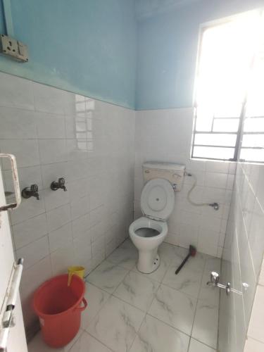 a bathroom with a toilet and a red bucket at Tenzing Homestay in Kalimpong