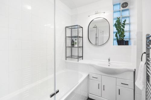 a white bathroom with a sink and a mirror at Stylish 2 bed Central London in London