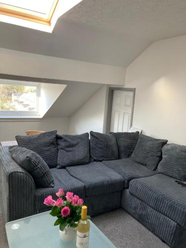 a living room with a black couch and pink flowers at Skylight Loft, 2 bed apartment, central Lancaster in Lancaster