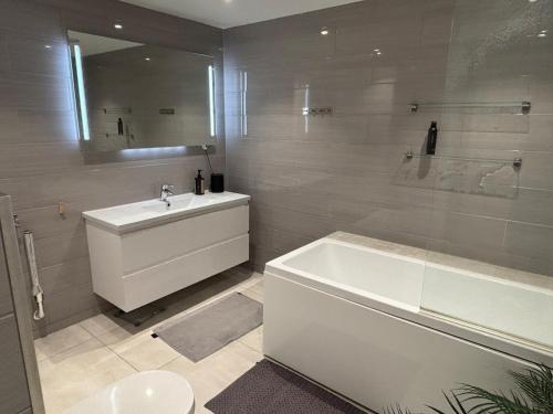 a bathroom with a white tub and a sink and a bath tub at Nordic Comfort Suite with Hot Tub in Storeidet