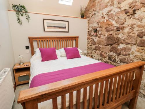 a bedroom with a bed and a stone wall at Cygnet Cottage in Berwick-Upon-Tweed