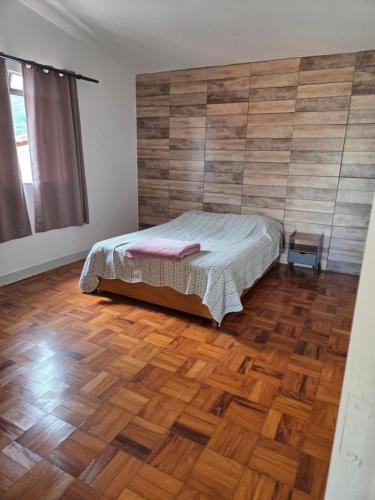 a bedroom with a bed and a wooden floor at Casa confortável e central in Poços de Caldas