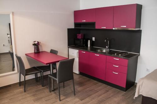 małą kuchnię z czerwonymi szafkami i czerwonym stołem w obiekcie Rooms Rebolj w mieście Osijek