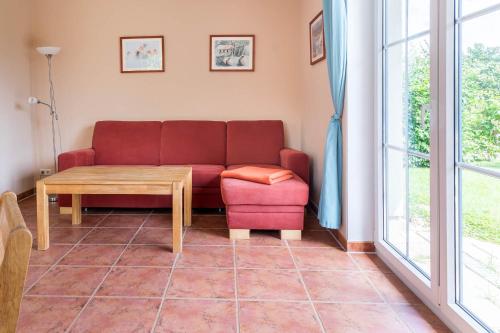 a living room with a red couch and a table at Ferienwohnung Katharina EG in Wohlenberg