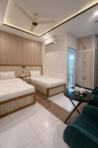 a hotel room with two beds and a couch at Hotel Noor Sky in Islamabad