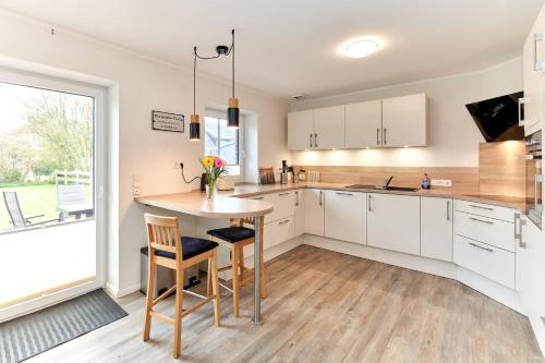 a kitchen with white cabinets and a table with chairs at Deichläufer in Ockholm