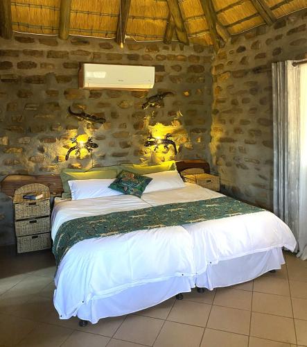 a bedroom with a large bed in a stone wall at Outeniqua Guest Farm in Okahandja