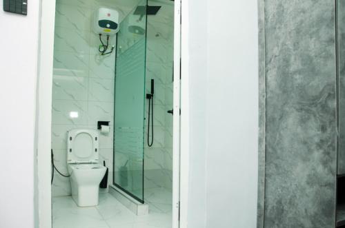 a bathroom with a toilet and a glass shower at El-Nido Hotel by Kdove in Omole