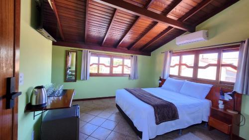 a bedroom with a bed and a table and windows at Recanto da Dona Luiza - Pousada in Florianópolis