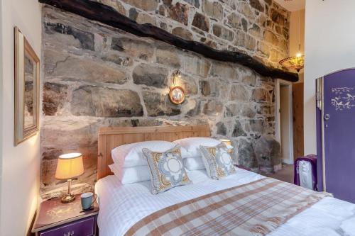 a bedroom with a bed and a stone wall at 4 Bed in Arthog oc-b31966 in Arthog