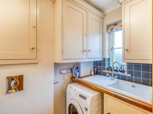 a kitchen with white cabinets and a washer and dryer at 2 Bed in Chathill oc-77990 in Ellingham