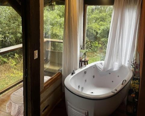 a bath tub in a bathroom with a window at Espaço Casa da Árvore - 3 opções de chalés in Ouro Preto