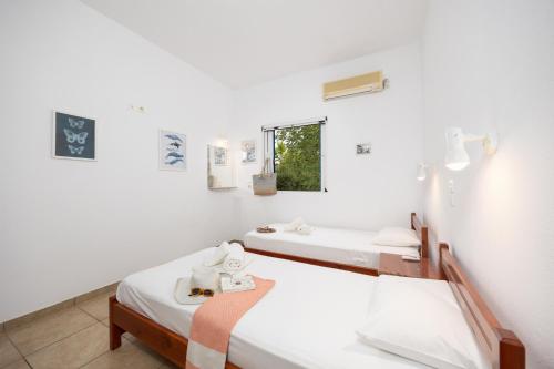 a white room with two beds and a window at Villa Calliope Kalamaki in Kalamaki
