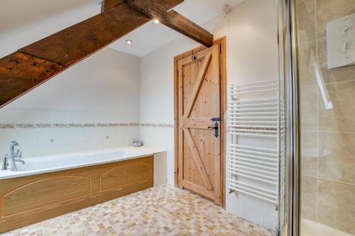 a bathroom with a bath tub and a wooden door at 2 Bed in Exminster oc-h28725 in Exminster