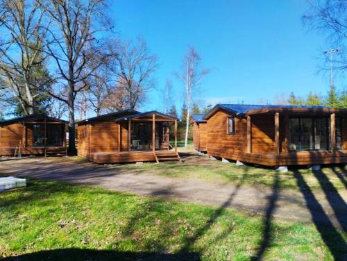 two large wooden cabins in a field with trees at Chalet 3 étoiles - Piscine - ccbbgcc in Sauxillanges