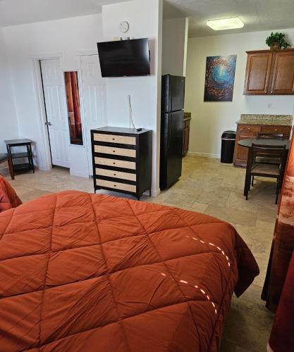 a bedroom with a large orange bed and a kitchen at Blue Heron Bridge Hotel and Dive Club in Riviera Beach