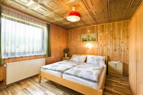 a bedroom with a bed in a room with wooden walls at Pension Stausee in Sankt Jakob im Rosental