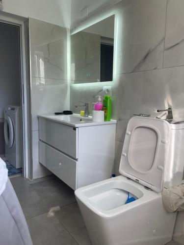a white bathroom with a toilet and a sink at Peaceful House in Përmet