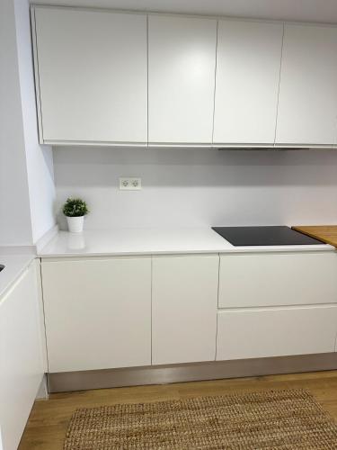 a white kitchen with white cabinets and a potted plant at 60m2 Cozy Apartament in Valencia