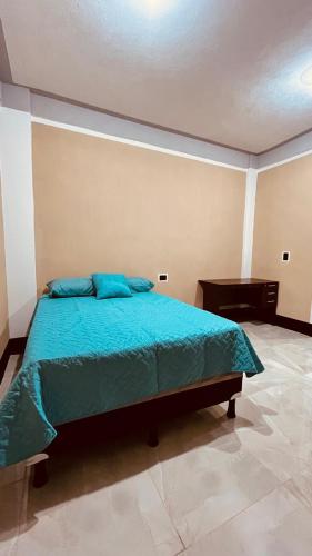 una camera da letto con un letto con lenzuola blu e un pianoforte di hidden house shared apartment a San Juan La Laguna