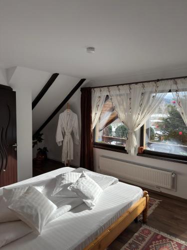 a bedroom with a white bed with a window at Casa Csiki in Râşnov