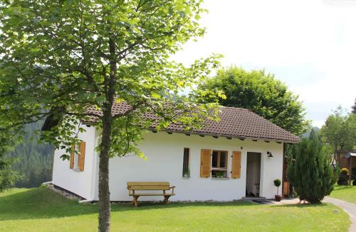 a small white house with a bench in the yard at Ferienhaus Bruno - Südhanglage mit 2 Schlafzimmern in Feldberg