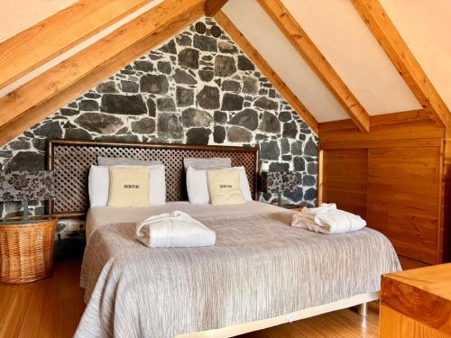 a bedroom with two beds and a stone wall at Palheiros do Serrado by Real Vision in Estreito da Calheta