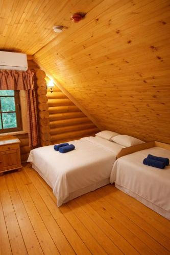 two beds in a room with wooden walls and wood floors at Jugland-Private Riverside Retreat with Sauna & Hot Tub in Bajāri