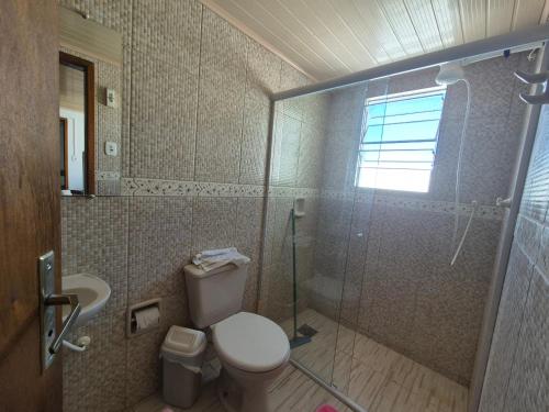 a bathroom with a toilet and a glass shower at Apartmento 3 in Santa Vitória do Palmar