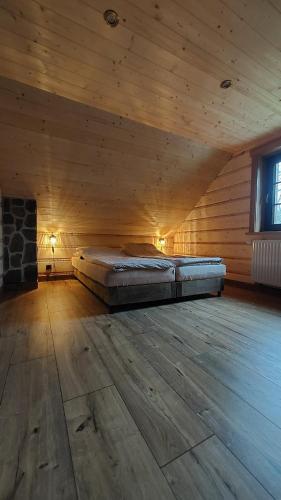 a large room with a bed in a wooden cabin at Domek u Hillów in Stronie Śląskie